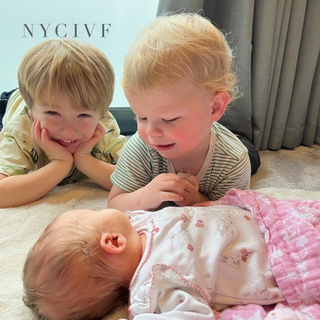 Two toddlers lying beside their newborn sister