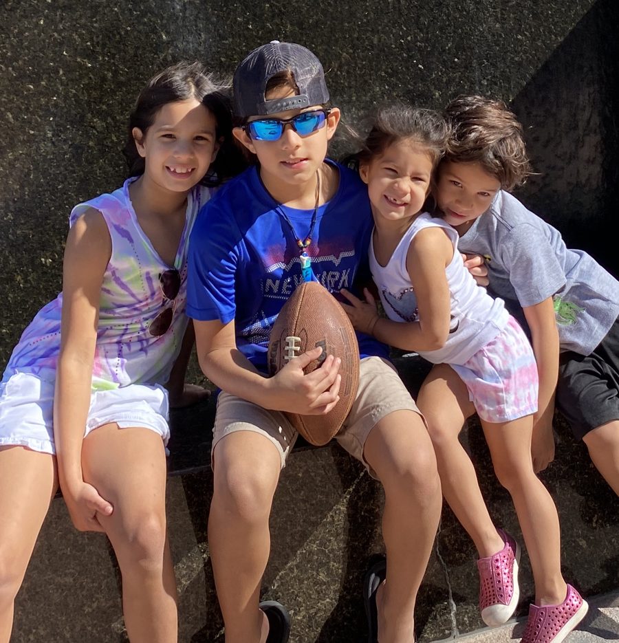 Four smiling children sitting together outdoors