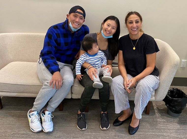 Dr. Elassar with a family and their toddler on a sofa