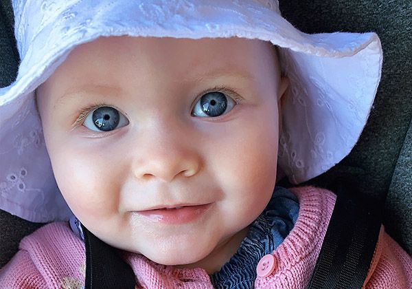 A smiling baby in a white sun hat