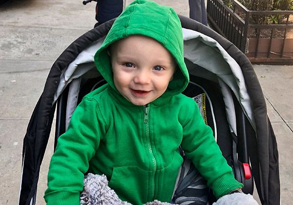 A smiling toddler in a green hoodie