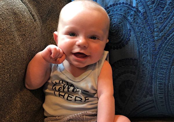 A smiling baby sitting on a sofa